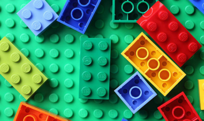 Des Lego de différentes couleurs sont éparpillés sur une surface verte, elle-même en Lego.